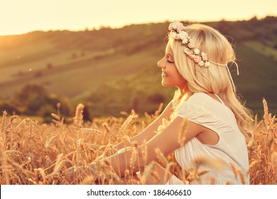 Beautiful young woman sitting in wheat and enjoy - Powered by Shutterstock