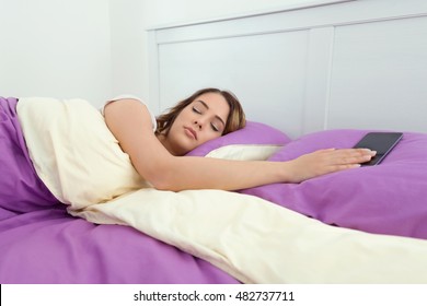 Beautiful Young Woman Is Sleeping In Bed While Her Phone Is Ringing Next To Her