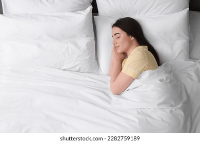 Beautiful young woman sleeping in soft bed, top view