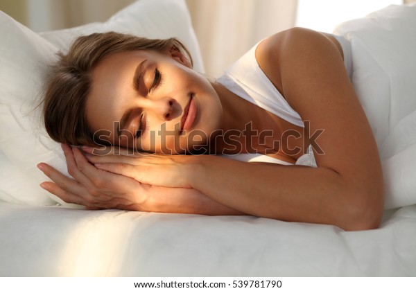 快適に幸せにベッドに寝ながら眠る美しい若い女性 彼女の顔に日の光の夜明け の写真素材 今すぐ編集