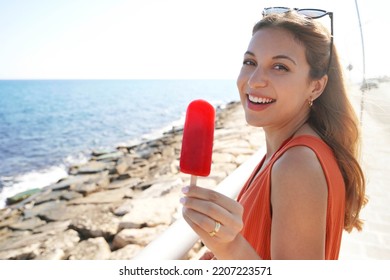 Beautiful Young Woman Smiling With An Icicle Popsicle In Her Hand On Summer. Looks At Camera.