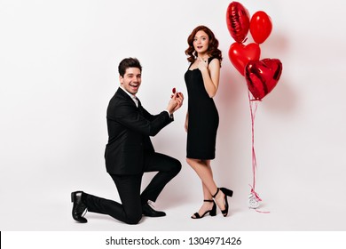 Beautiful young woman smiling while boyfriend making proposal. Studio shot of loving couple with wedding ring. - Powered by Shutterstock