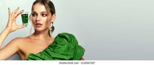 A beautiful young woman with smooth tanned skin holds a glass of green juice in her hand. The concept of advertising natural cosmetics. Cleansing the body, juice diet. Detox for the body.