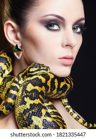 beautiful young woman with Snake. Brunette girl with fashion perfect make up. Beauty close up studio shot. jewelry earrings