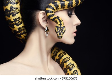beautiful young woman with Snake on her head like a hair.Brunette model girl with fashion make up. Beauty jewelry earrings