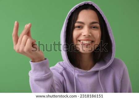 Beautiful young woman snapping fingers on green background, closeup