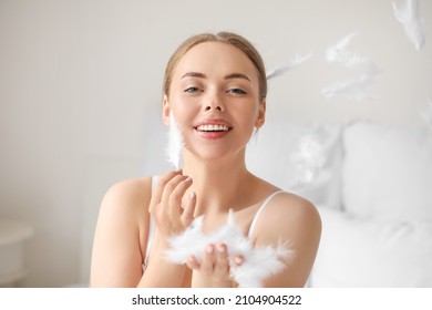 Beautiful Young Woman With Soft Feathers In Bedroom