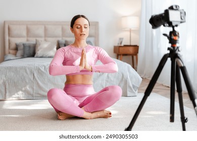 Beautiful young woman in sportswear doing yoga at home and recording blog. Fitness blogger recording video for her blog - Powered by Shutterstock