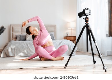 Beautiful young woman in sportswear doing yoga at home and recording blog. Fitness blogger recording video for her blog - Powered by Shutterstock