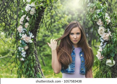 Beautiful Young Woman In A Spring Park With A Wreath Of Flowers Holding Herself Over Thick Long Hair