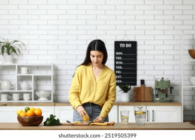 Beautiful young woman squeezing lemon in juicer for preparing infused water in kitchen - Powered by Shutterstock