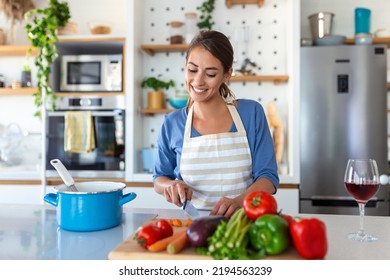 Beautiful young woman stand at modern kitchen chop vegetables prepare fresh vegetable salad for dinner or lunch, young woman cooking at home make breakfast follow healthy diet, vegetarian concept - Powered by Shutterstock