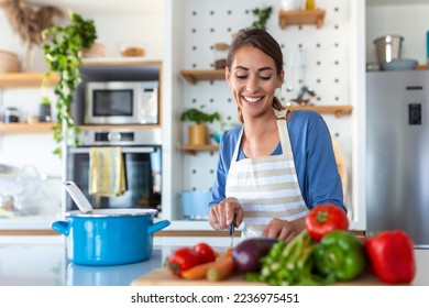 Beautiful young woman stand at modern kitchen chop vegetables prepare fresh vegetable salad for dinner or lunch, young woman cooking at home make breakfast follow healthy diet, vegetarian concept - Powered by Shutterstock