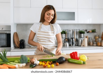 Beautiful young woman stand at modern kitchen chop vegetables prepare fresh vegetable salad for dinner or lunch, young woman cooking at home make breakfast follow healthy diet, vegetarian concept - Powered by Shutterstock