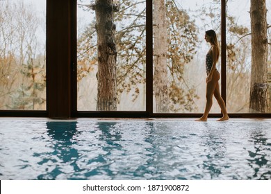 Beautiful Young Woman Standing By The Window At Indoor Swimming Pool In Spa