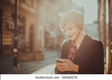 Beautiful young woman standing at the street and using her mobile phone