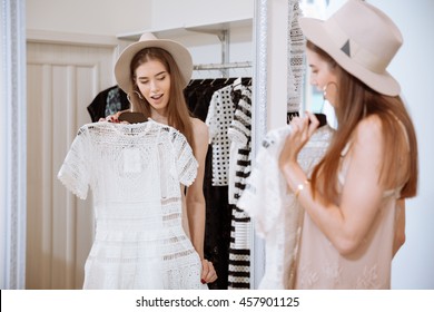 Beautiful Young Woman Standing And Trying On Dress In Front Of Mirror