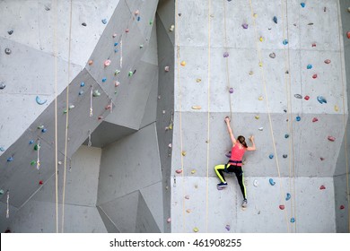 Beautiful young woman starts to climbing big artificial wall - Powered by Shutterstock