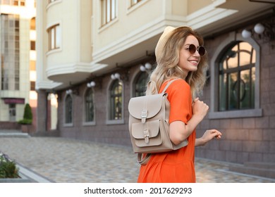 Beautiful young woman with stylish backpack outdoors. Space for text