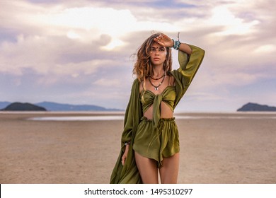 beautiful young woman in stylish costume on the beach at sunset