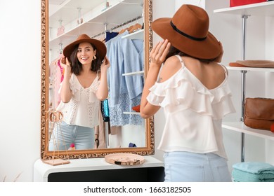 Beautiful Young Woman With Stylish Hat Near Mirror In Shop