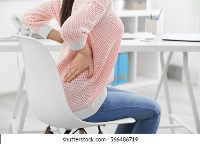 Beautiful young woman suffering from backache in office