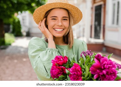 beautiful young woman in summer style outfit smiling happy walking with flowers in city street wearing straw hat fashion trend, peony, white teeth candid - Powered by Shutterstock