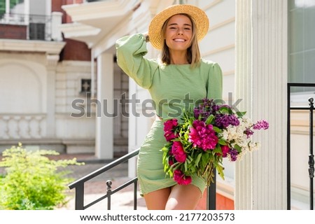 beautiful young woman in summer style outfit smiling happy walking with flowers in city street wearing straw hat fashion trend, peony garden