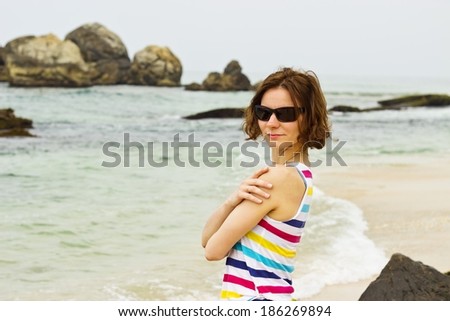 Beautiful young woman in sunglasses portrait on the empty beach at coastline of Sri Lanka, Ceylon. Horizontal image