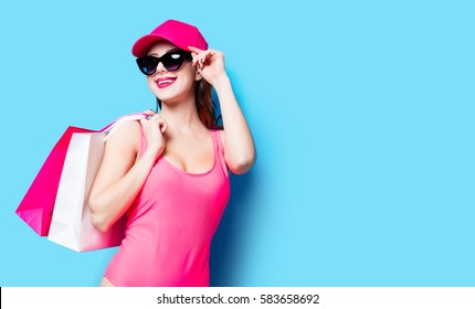 Beautiful Young Woman In Swimsuit With Shopping Bags Standing On The Wonderful Blue Background