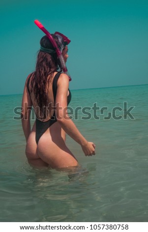 Beautiful young woman in swimsuit with snorkeling mask having fun in the sea water over sky background. Pretty girl enjoying sunny summer day on her beach tropical holiday