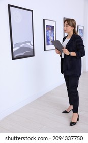 Beautiful Young Woman With Tablet At Exhibition In Art Gallery