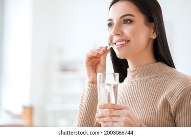 Beautiful young woman taking pills at home - Powered by Shutterstock