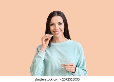 Beautiful young woman taking pills on color background - Shutterstock ID 2092318030