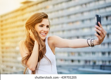 Beautiful young woman taking selfie in city - Powered by Shutterstock