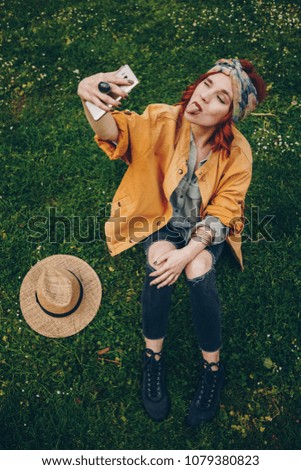 Similar – Blonde junge Frau mit Hut und Sonnenbrille, die bei Sonnenuntergang im Wald mit einem Mobiltelefon ein Foto macht.