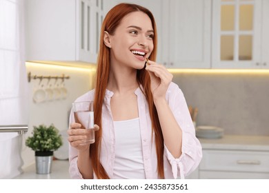 Beautiful young woman taking vitamin pill at home - Powered by Shutterstock