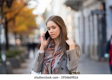 Schöne junge Frau, die auf dem Smartphone auf der Straße spricht