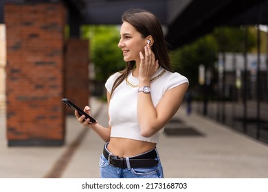 Beautiful Young Woman Talking Phone On Air Pods On The Street