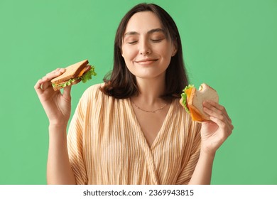 Beautiful young woman with tasty sandwiches on green background - Powered by Shutterstock