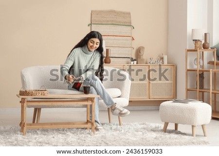 Beautiful young woman with teapot of hot tea at home