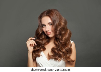 Beautiful young woman touching her long wavy and shiny hair. Brunette woman with curly hairstyle portrait
