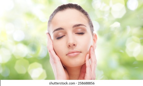 Beautiful Young Woman Touching Her Radiant Face Skin With Eyes Closed On Green Background