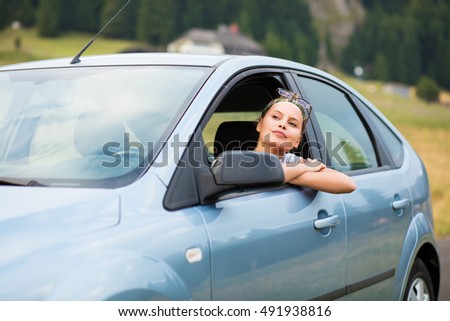 beautiful young woman traveling, admiring nature from the car door with the window left down