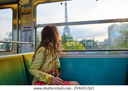 Beautiful young woman travelling in a train of Parisian underground and looking through the window at the Eiffel tower