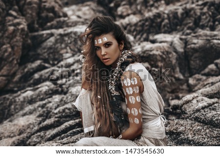 beautiful young woman in tribal costume with primal ornamet on skin outdoors
