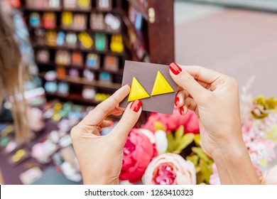 Beautiful young woman trying on a pair of modern bright earrings at handmade jewelry shop - Powered by Shutterstock