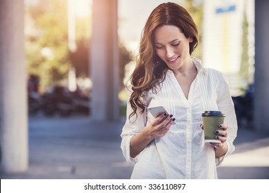 beautiful young woman is using an app in her smartphone device to send a text message in front of a sunset background - Powered by Shutterstock