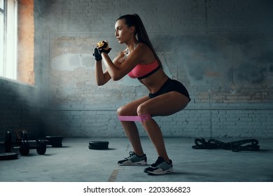 Beautiful young woman using elastic resistance band while exercising in gym - Shutterstock ID 2203366823