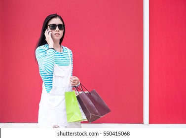 Beautiful Young Woman Using Her Smartphone While Doing Some Shopping In A Mall.